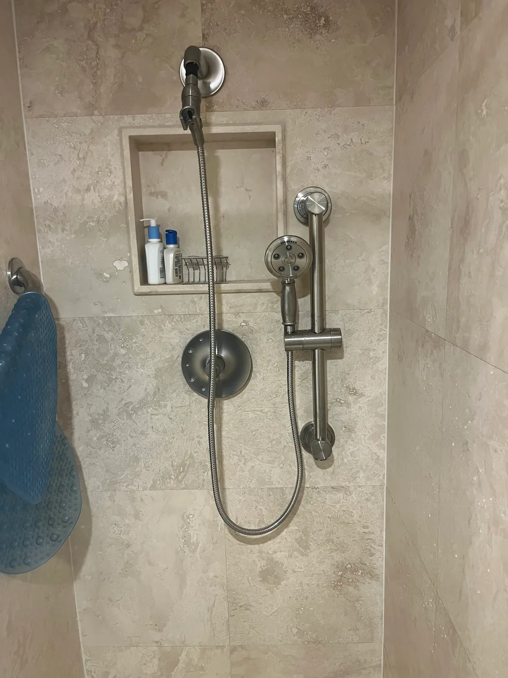 Handheld shower head, slide bar, and valve trim in a tiled West Palm Beach shower